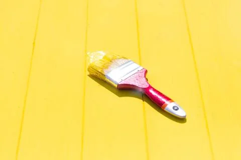 Bright lighting. A hard shadow falls on the brush. Yellow wooden background i Stock Photos