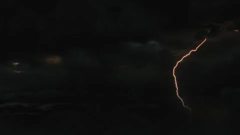Bright lightning bolts striking through dark storm clouds at night with Vídeo Stock 344634945