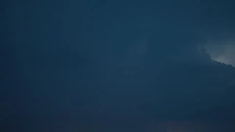 Bright lightning flashes behind dark rolling storm clouds Stock Footage 337854200