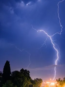 Bright lightning sparkles with a beautiful pattern in the evening sky over the Stock Photos