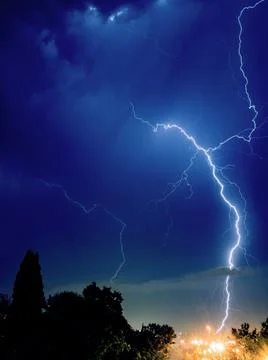 Bright lightning sparkles with a beautiful pattern in the evening sky over the Stock Photos