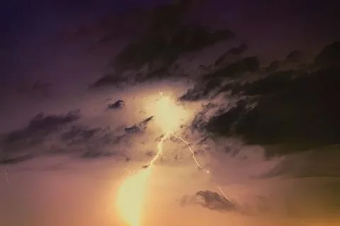 Bright lightning strikes through dark stormy clouds at night Stock Photos