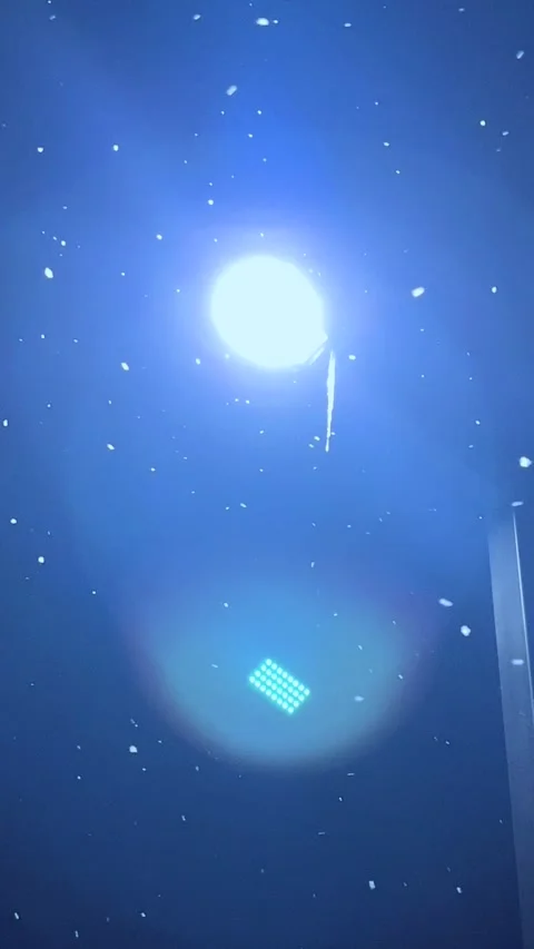 Bright Lights Shine in Dark Sky With Snow Falling Near a Street in a Winter Stock Footage 327912617