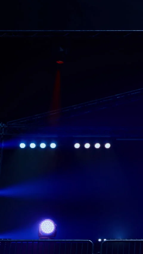 Bright lights shine at a stage during a nighttime event with a dark sky Stock Footage 334171996