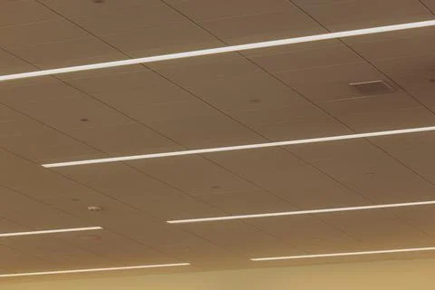 Bright linear  lights stretch across the airport terminal ceiling. Stock Photos
