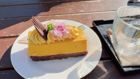 A bright mango cheesecake slice served on a white plate Stock Footage 338130630