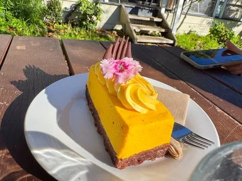 A bright mango cheesecake slice served on a white plate Stock Photos