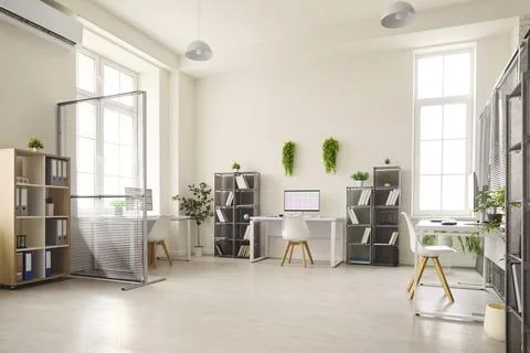 Bright modern office workspace with computers, partitions and indoor plants Stock Photos