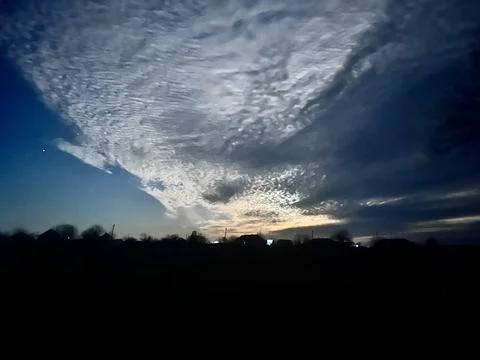 Bright moon piercing through dark scattered clouds in night sky Fotos de archivo