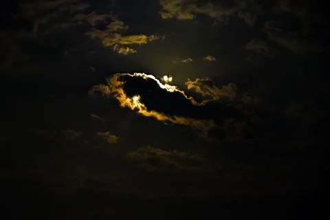 Bright moonlight breaks through dark clouds at night Stock Photos