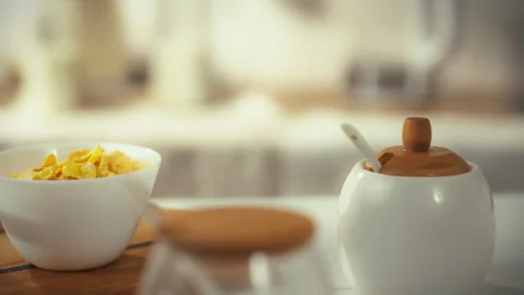 Bright morning setup with cereal and sugar on a wooden table in a cozy kitch Stock Footage 323731269
