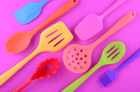 Bright multi colored kitchen utensils on purple background Stock Photos