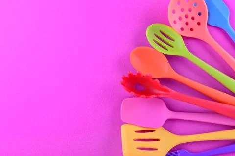 Bright multi colored kitchen utensils on purple background with copy space Stock Photos