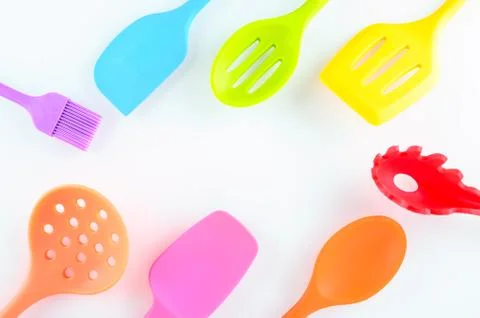 Bright multi colored kitchen utensils on white background with copy space Stock Photos