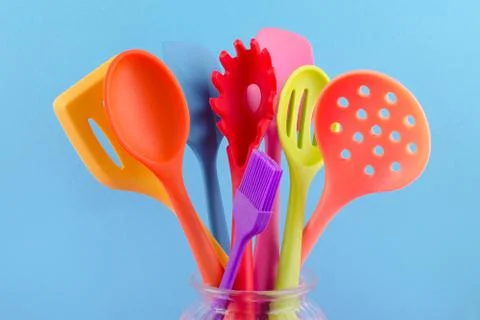 Bright multi colored kitchen utensils on blue background Stock Photos