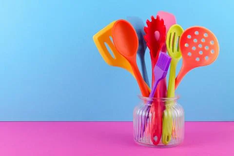Bright multi colored kitchen utensils on blue and purple background with copy Stock Photos