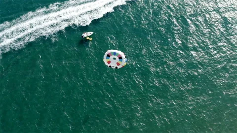 A bright multi-colored parachute with tourists takes off into the sky above the Stock-Footage 118659547
