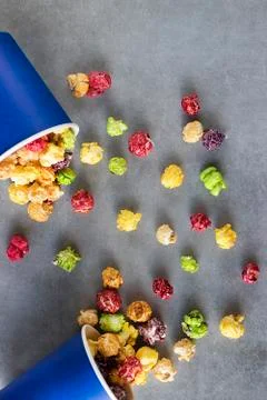 Bright multi-colored popcorn in blue paper cups on gray background. Stock Photos