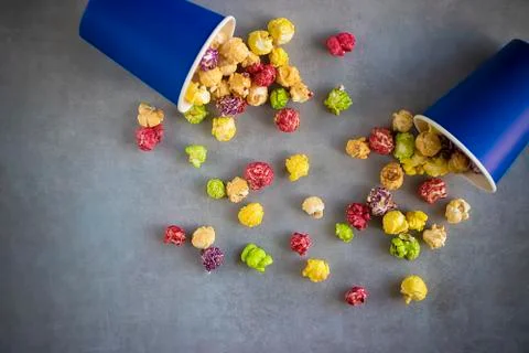 Bright multi-colored popcorn in blue paper cups on gray background. Stock Photos