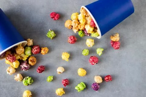 Bright multi-colored popcorn in blue paper cups on gray background. Stock Photos
