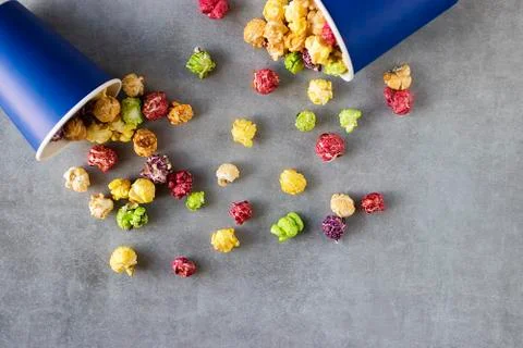 Bright multi-colored popcorn in blue paper cups on gray background. Stock Photos