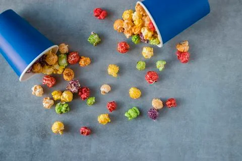 Bright multi-colored popcorn in blue paper cups on gray background. Stock Photos