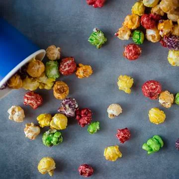 Bright multi-colored popcorn in blue paper cups on gray background. Stock Photos