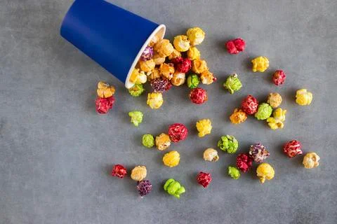 Bright multi-colored popcorn in blue paper cups on gray background. Stock Photos