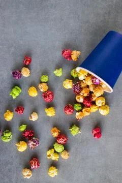 Bright multi-colored popcorn in blue paper cups on gray background. Stock Photos