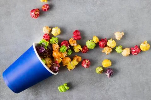Bright multi-colored popcorn in blue paper cups on gray background. Stock Photos