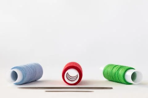 Bright multi-coloured sewing threads on a white fabric background and copy sp 스톡 사진