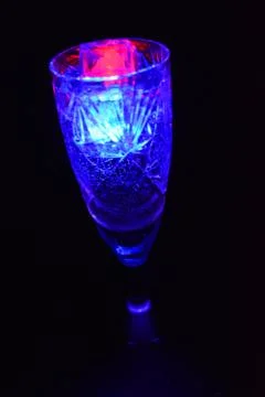 Bright multicolor doidic glowing ice cubes float in the drink. Stock Photos