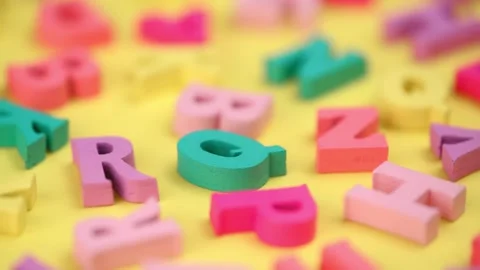 Bright multicolored letters rotating on a yellow background. side view. closeup. Stock-Footage 247111158