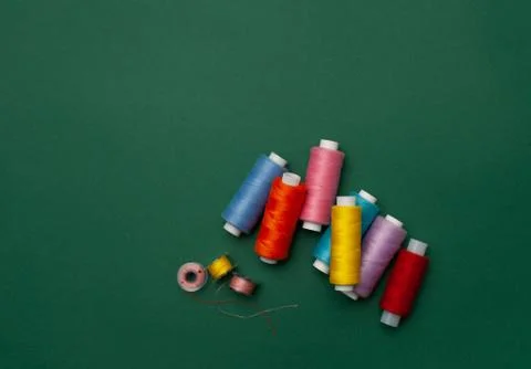 Bright multicolored sewing thread on a dark green background Stock Photos