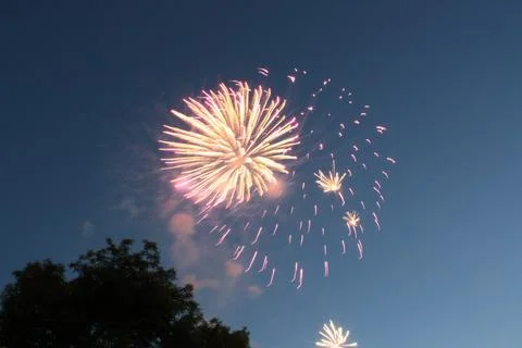 Bright multiple fireworks bursting in the blue evening sky Stock Photos