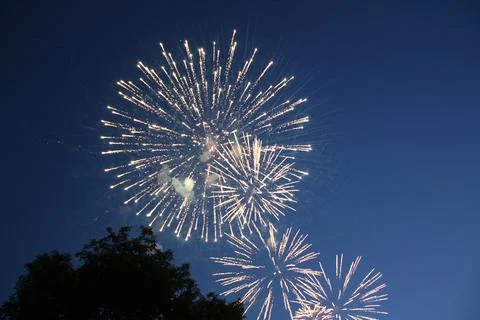 Bright multiple fireworks explosions bursting in the twilight sky Stock Photos