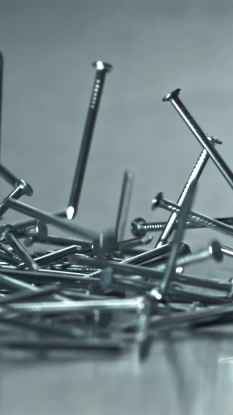 Bright Nails Flung Across Textured Surface with Cool Tones Filmed on a high Stock Footage 335395457
