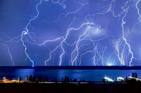 Bright night flash of lightning over the river Stock Photos