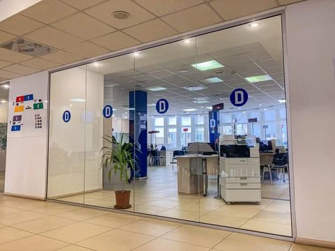 A bright office interior with desks, computers, printers, posters, and a pott Stock Photos