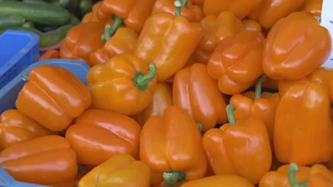 Bright orange bell peppers in crates with glossy skins and green stems, piled Video stock 321816331