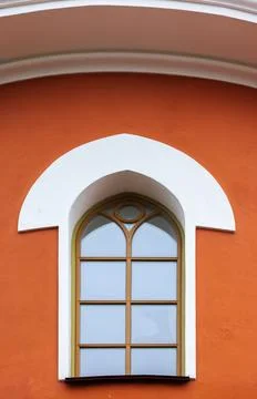 Bright orange building facade features a white rounded arch and a tall arch.. Fotos de archivo