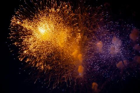 A bright orange firework and next to it a blue firework with sparks on the Stock Photos