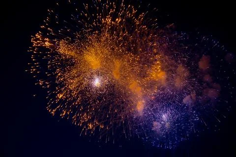 A bright orange firework and next to it a blue firework with sparks on the Stock Photos