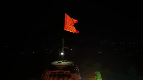 Bright orange flag billows in the night wind atop a dark ancient Hindu ston.. Stock Footage 305989314