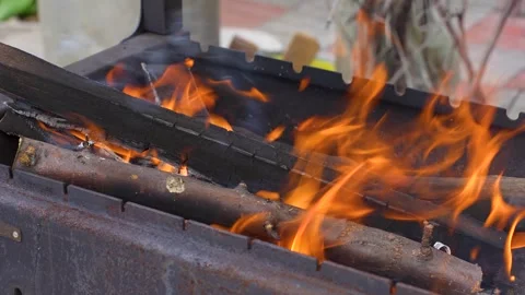 Bright orange flames and glowing embers burning inside a metal charcoal gri.. Stock Footage 346122079