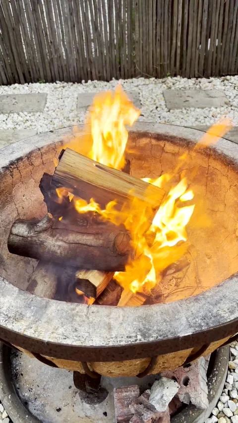 Bright orange flames burning on firewood inside concrete fire pit outdoors. Stock Footage 337785950