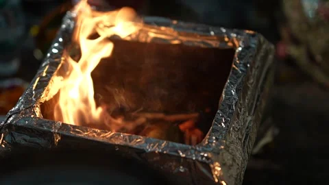 Bright orange flames flicker inside a square metallic ritual vessel 스톡 동영상 335270754
