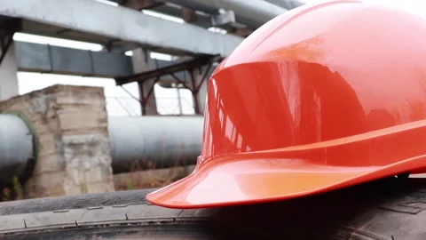 Bright orange hard hat rests on tire near industrial scaffolding Stock-Footage 295347076