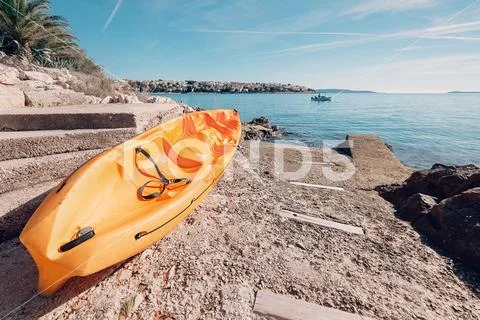 Bright orange kayak is on the sea pier Stock Photos