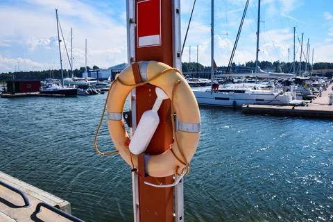 Bright orange life ring hangs beside a dock post Stock Photos